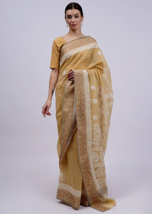 Model wearing a golden saree with light floral embroidery and an ornate border.